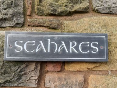 A sign with the name seahares mounted on a stone wall at Seahares in Seahouses