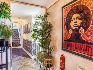 A hallway with patterned stairs and wall decor including a framed artwork and plants at Clematis House in St Columb Major