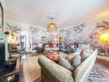 A living room with sofas armchairs a coffee table rug and a decorative wall at Clematis House in St Columb Major
