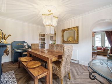 A dining room with a wooden table wicker chairs and a blue piano at Clematis House in St Columb Major