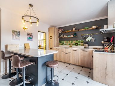 A kitchen with a marble countertop island and wooden cabinets at Clematis House in St Columb Major
