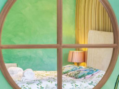A bedroom with a bed with floral bedding and a lamp next to it at Clematis House in St Columb Major