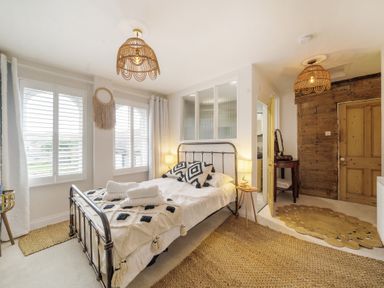 A bedroom with a double bed pillows and folded towels by the windows at Clematis House in St Columb Major