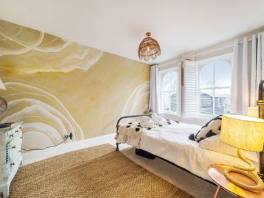 A bedroom with a bed a wooden dresser and two windows with shutters at Clematis House in St Columb Major