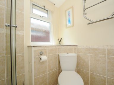 A bathroom with a toilet paper holder a window and a towel rack at Little Trebah Atlantic Bays Holiday Park near St Merryn