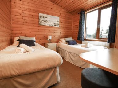 A bedroom with two single beds a window and a small table at Seascape Retreat in Ilfracombe