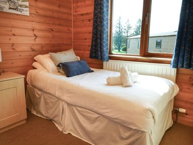A small bedroom with a single bed beside a window with blue curtains at Seascape Retreat in Ilfracombe