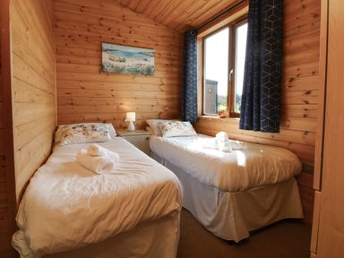 A bedroom with two single beds bedside table lamp and a window with curtains at Seascape Retreat in Ilfracombe