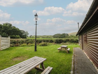 A garden with two wooden picnic tables a vintage lamp post and a wooden cabin at Ash in Swanage