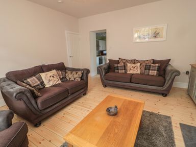 A living room with two brown sofas with cushions a wooden coffee table and a rug at 55 Wellwood Street in Amble