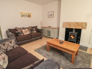 A living room with two sofas a wooden coffee table a fireplace and a sideboard at 55 Wellwood Street in Amble