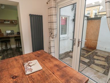 A wooden table near glass doors leading to a small outdoor area with paving stones at 55 Wellwood Street in Amble
