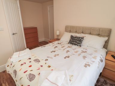 A bedroom with a double bed a bedside table lamp a chest of drawers and folded towels on the bed at 55 Wellwood Street in Amble