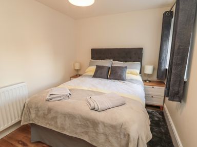 A bedroom with a double bed two bedside tables with lamps and folded towels on the bed at 55 Wellwood Street in Amble