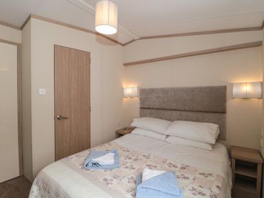 A bedroom with a double bed two bedside tables and folded towels at Beech in Swanage