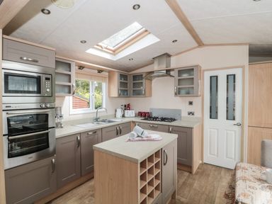 A kitchen with a central island and built in oven and microwave at Birch in Swanage