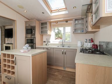 A kitchen with an island countertop a microwave oven and gas stove at Birch in Swanage