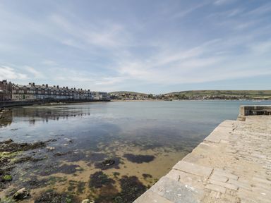 A coastal view with a stone pier and houses along the shoreline at Birch in Swanage