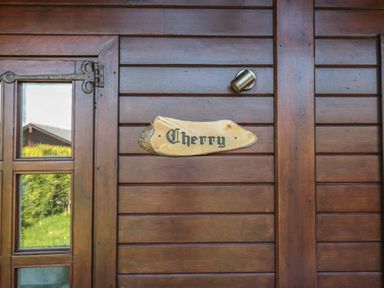 A wooden door with glass panels and a wooden sign that says Cherry at Cherry in Swanage