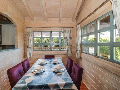 A dining area with a table set for four with purple chairs and blue window frames at Cherry in Swanage