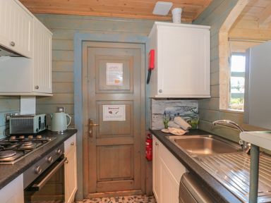 A kitchen with a stove oven toaster kettle sink and cabinets at Cherry in Swanage