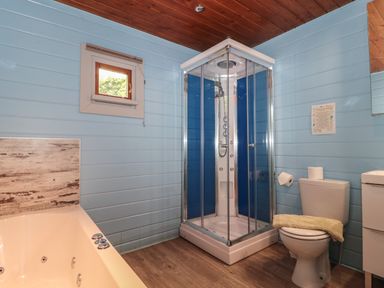 A bathroom with a shower enclosure bathtub toilet and small window at Walnut in Swanage