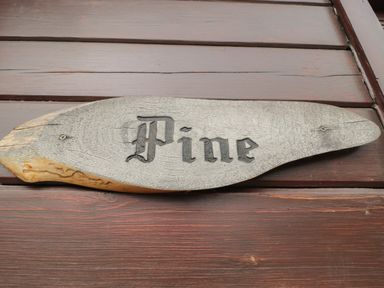 A wooden sign with the word Pine mounted on a wooden wall at Pine in Swanage