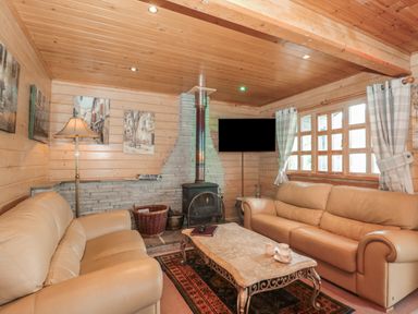 A living room with two beige sofas a stone fireplace a wooden ceiling and a coffee table at Pine in Swanage