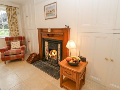 A living room with a fireplace reading chair and a side table with a lamp and fruit bowl at Crookham Dairy Crookham near Etal