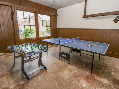 A game room with a foosball table and a ping pong table with paddles and ball at Crookham Dairy Crookham near Etal