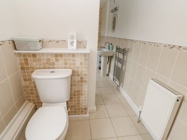A bathroom with a toilet sink radiator and a metal towel rack at Crookham Dairy in Crookham near Etal