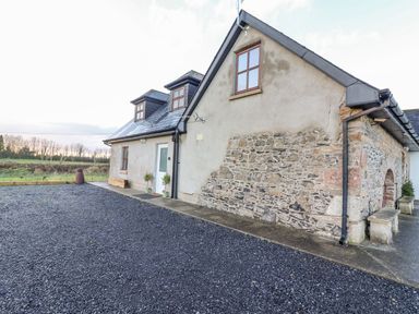 An exterior view of a stone and stucco house with gravel driveway at The Artist's Barn in Ayle near Cappawhite