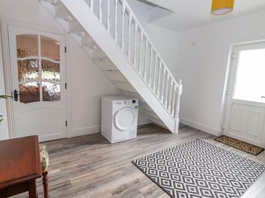 A hallway with stairs a washing machine a patterned rug and a wooden table at The Artist's Barn in Ayle near Cappawhite
