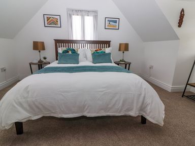 A bedroom with a double bed two bedside tables with lamps and two paintings on the wall at The Artist's Barn in Ayle near Cappawhite