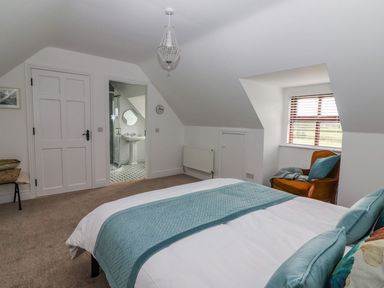 A bedroom with a bed a chair and an open door to a bathroom at The Artist's Barn in Ayle near Cappawhite