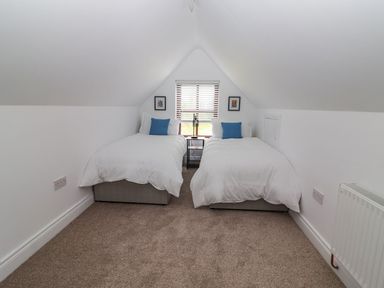 A bedroom with two single beds a window between them and a nightstand at The Artist's Barn in Ayle near Cappawhite