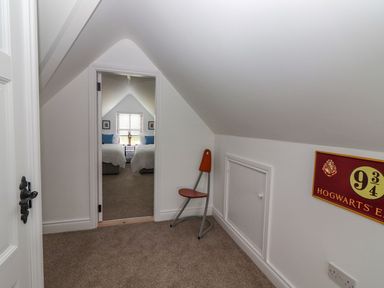 A small room with a chair and a door leading to a bedroom with two beds at The Artist's Barn in Ayle near Cappawhite