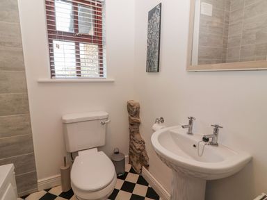 A bathroom with a toilet and a sink with faucets and a mirror above at The Artist's Barn in Ayle near Cappawhite
