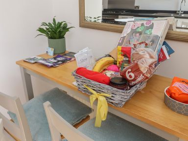 A table with a plant and a basket filled with snacks at Bluebell Cottage in Brayton