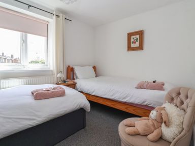 A bedroom with two beds and a chair at Bluebell Cottage in Brayton