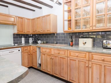 A kitchen with wooden cabinets dishwasher toaster and a sink at Foxglove Barn in South Brent