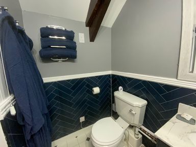 A bathroom with a toilet towels hanging on the wall and a marble countertop at Foxglove Barn in South Brent