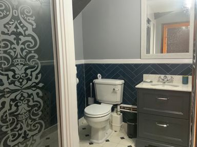 A bathroom with a toilet sink vanity mirror and patterned glass door at Foxglove Barn in South Brent