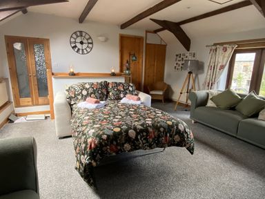 A living room with a sofa bed and chairs at Foxglove Barn South Brent