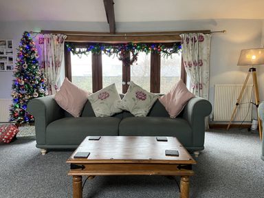 A living room with a sofa and Christmas tree at Foxglove Barn South Brent