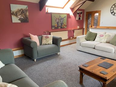 A living room with sofas and wall art at Foxglove Barn in South Brent