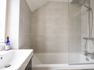 A bathroom with a white sink bottle a bathtub and a shower area at Conybeare Cottage in Lyme Regis