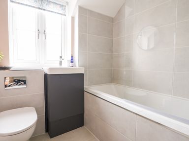 A bathroom with a toilet sink and bathtub with tiled walls and a window at Conybeare Cottage Lyme Regis