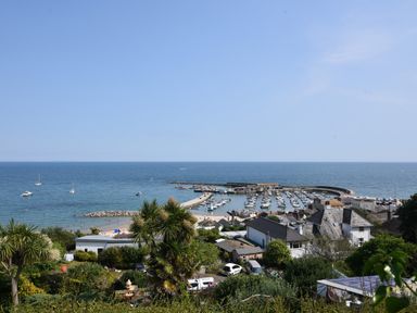 A coastal town with houses trees and a harbor with boats at Pendragon Pod in Axminster