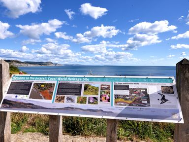 An information board about the Jurassic Coast World Heritage Site overlooking the sea and cliffs at Pendragon Pod in Axminster